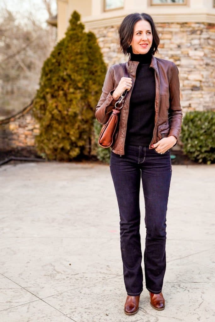 April from Stunning Style wearing a stylish winter outfit featuring a brown leather jacket, black top and denim pants.