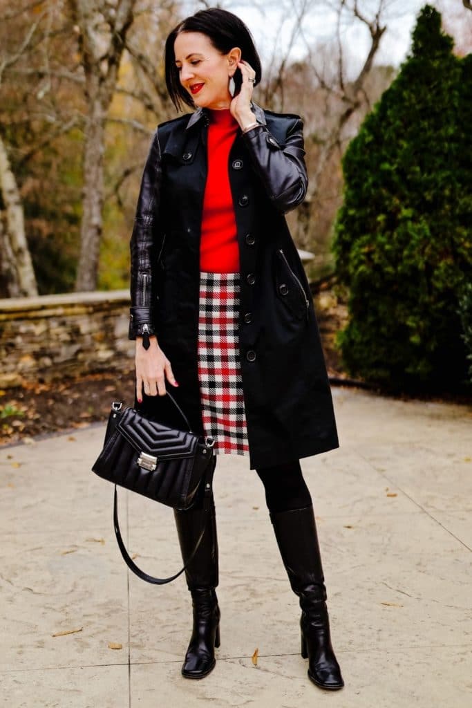 April from Stunning Style wearing a stylish winter outfit featuring a red top and plaid skirt with long black coat.