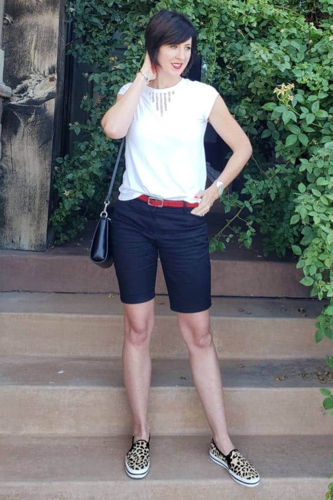 April from Stunning Style wearing a white top with navy Bermuda shorts.